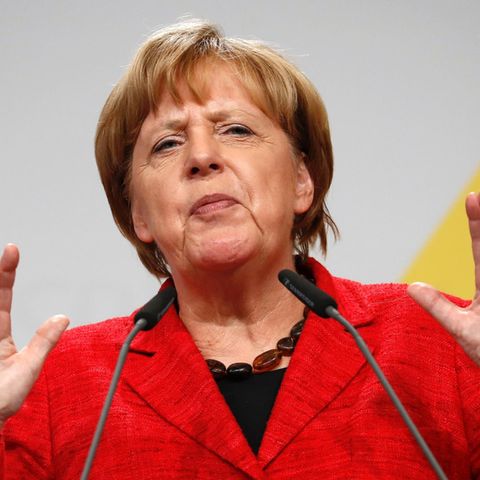 Angela Merkel mit verkniffenem Gesicht, hebt die Hände am Rednerpult