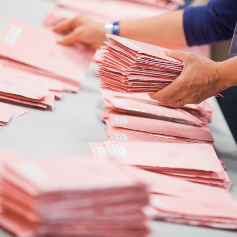 Rote Umschläge mit abgegebenen Briefwahlstimmen werden in Köln sortiert.