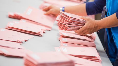 Rote Umschläge mit abgegebenen Briefwahlstimmen werden in Köln sortiert.