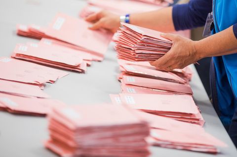 Rote Umschläge mit abgegebenen Briefwahlstimmen werden in Köln sortiert.