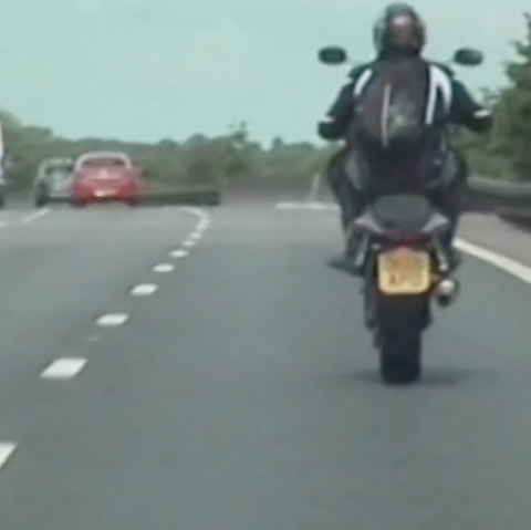 Ein Motorradfahrer macht auf der Autobahn M6 in England einen Wheelie: er fährt nur auf dem Hinterrad