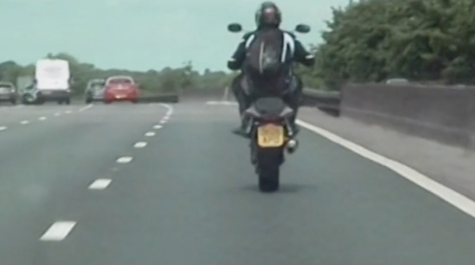 Ein Motorradfahrer macht auf der Autobahn M6 in England einen Wheelie: er fährt nur auf dem Hinterrad