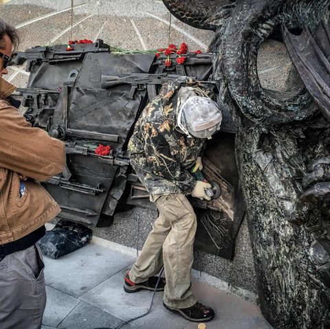 Panne auf Kalaschnikow-Denkmal: Mit einer Flex entfernen Arbeiter die Abbildung des Sturmgewehrs vom Typ StG 44