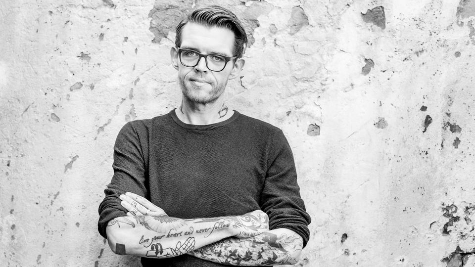 Nicholas Müller, ehemaliger Sänger der Band Jupiter Jones, steht vor einer Wand in Hamburg