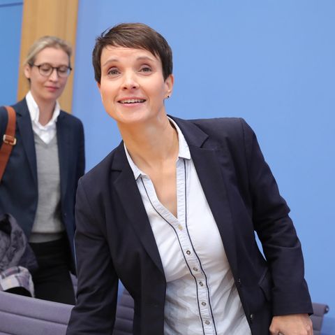 Lächelnd steht Frauke Petry auf der Bühne der Bundespressekonferenz an, hinter ihr geht AfD-Spitzenkandidatin Alice Weidel