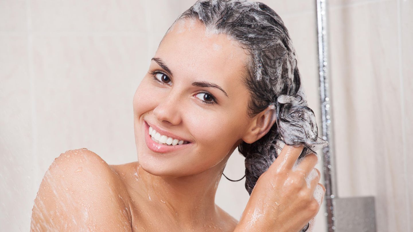 Eine Frau wäscht sich die Haare mit Shampoo.