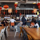 Tafeln an langen Tischen in der Bang Bang Oriental Foodhall: Wenn der Beeper blinkt und vibriert, den man bei der Bestellung erhält, kann das frisch zubereitete Essen abgeholt werden.