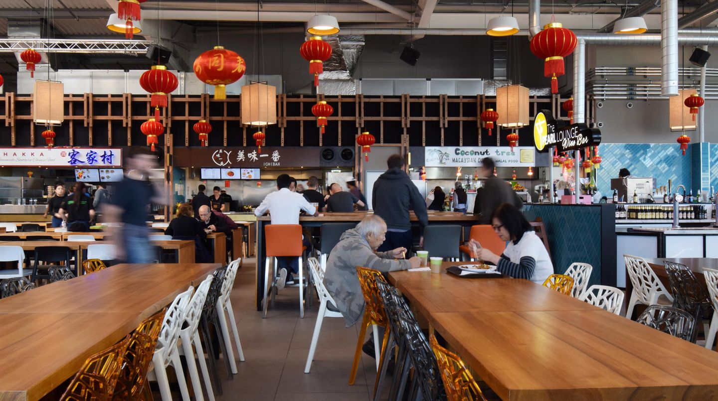 Tafeln an langen Tischen in der Bang Bang Oriental Foodhall: Wenn der Beeper blinkt und vibriert, den man bei der Bestellung erhält, kann das frisch zubereitete Essen abgeholt werden.