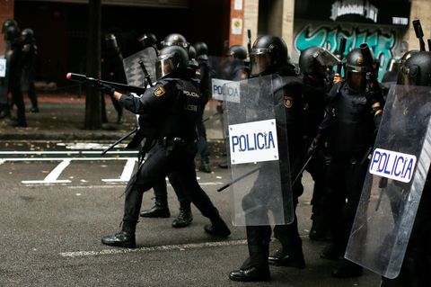 Ein spanischer Polizist zielt mit einem Gewehr für Gummigeschosse auf Befürworter des Referendums