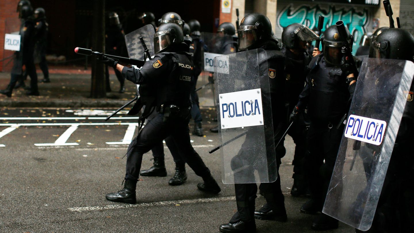 Ein spanischer Polizist zielt mit einem Gewehr für Gummigeschosse auf Befürworter des Referendums