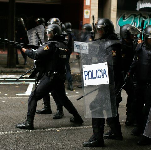 Ein spanischer Polizist zielt mit einem Gewehr für Gummigeschosse auf Befürworter des Referendums