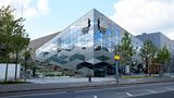 Von außen möchte der zweckmäßige Bau mit moderner Architektur beeindrucken: Das wie von Frank Gehry inspirierte Gebäude ist ein Werk des Londoner Architekturbüros Stiff + Trevillion.