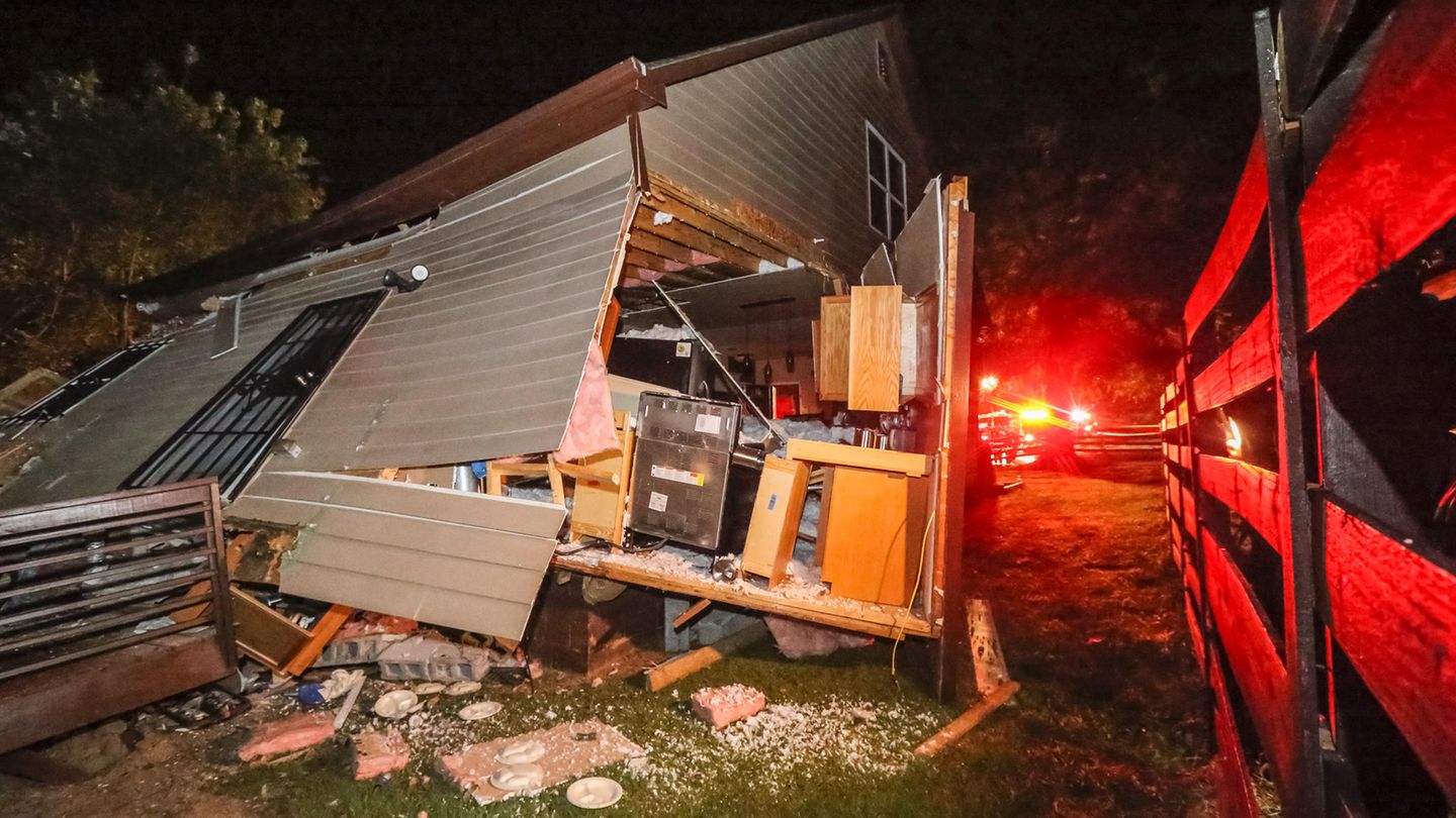 Feuerwehrleute stehen vor dem Haus, das von einem entgleisten Güterzug stark beschädigt wurde