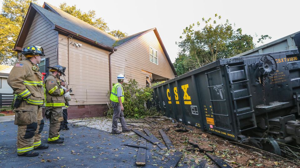 Feuerwehrleute stehen vor dem Haus, das von einem entgleisten Güterzug stark beschädigt wurde