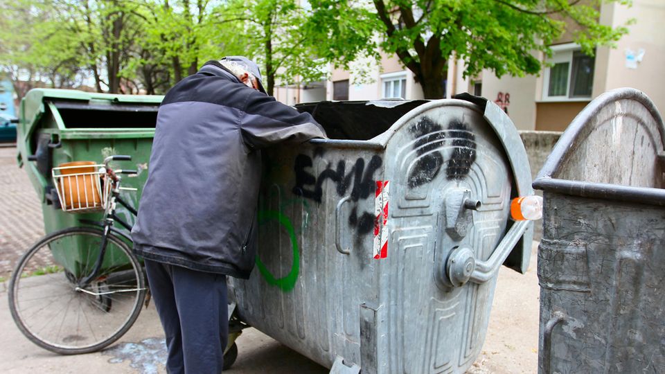 Obdachloser durchsucht Müllcontainer Obdachloser durchsucht Müllcontainer