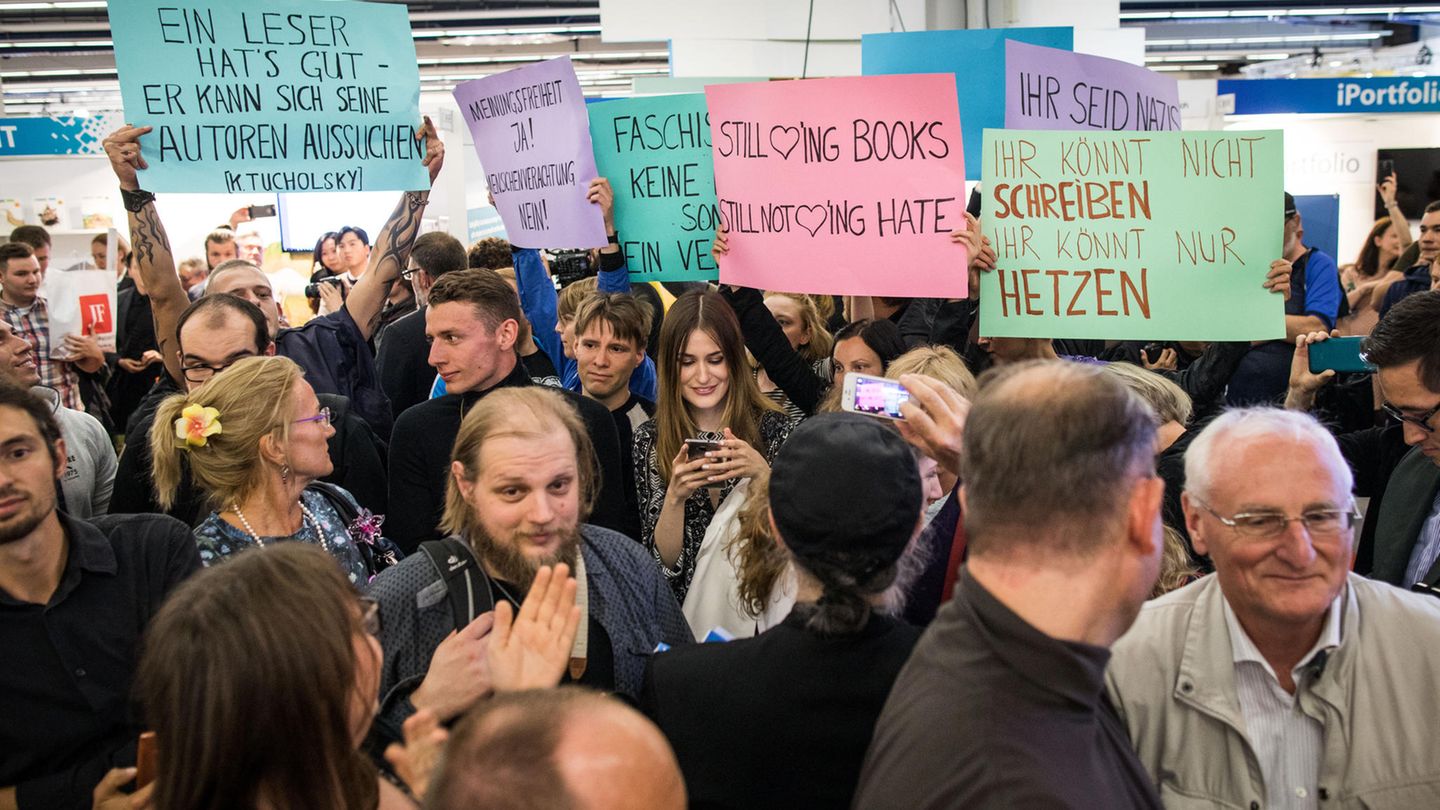 Demonstranten halten Protestplakate hoch. Sie tragen die Aufschriften "Ihr könnt nicht schreiben. Ihr könnt nur hetzen" oder "Meinungsfreiheit Ja! Menschenverachtung Nein!".