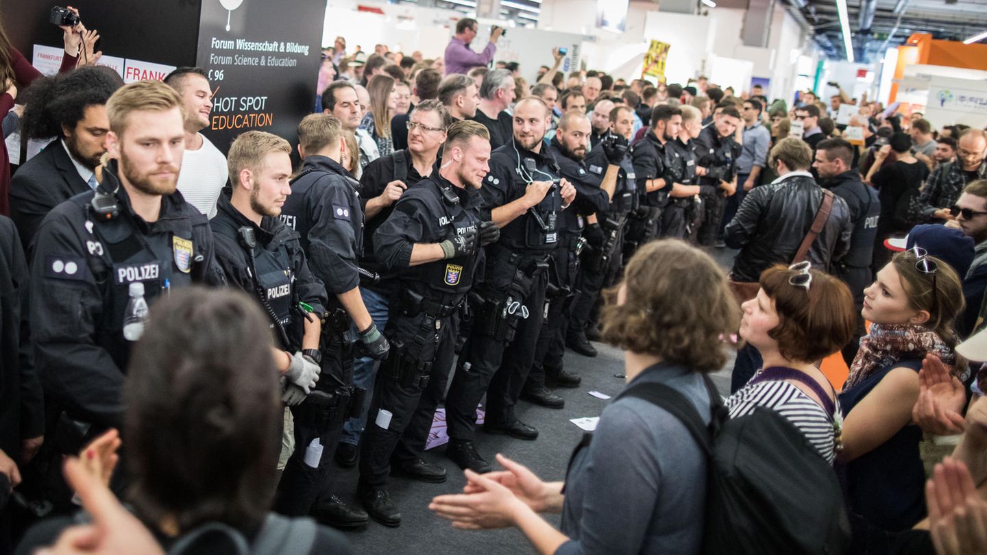 Demonstranten verhindern auf der Buchmesse in Frankfurt am Main die Fortsetzung einer Veranstaltung eines rechten Verlages. Polizisten bilden dabei eine Kette.