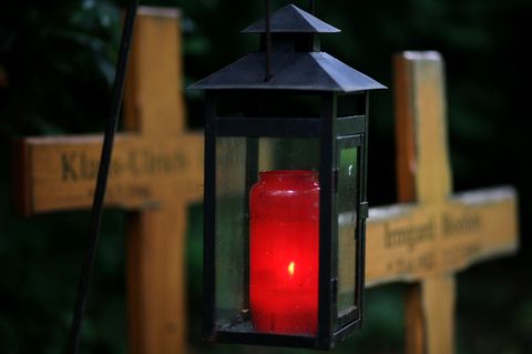 Ein Grablicht leuchtet zwischen zwei Holzkreuzen: Immer weniger Menschen entscheiden sich für Erd-Bestattungen