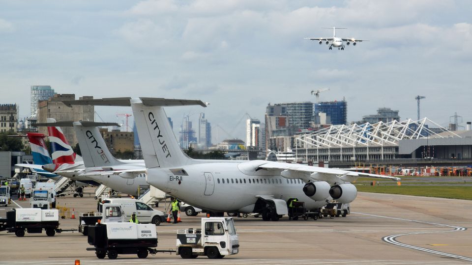 Steiler Anflug von Westen über den Finanial District: eine vierstahlige Avro RJ100 von Cityjet und weitere vor dem Terminal.
