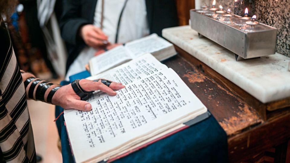 Orthodoxe jüdische Glaubensgemeinschaft: Ein Blick in das aufgeschlagene Gebetbuch. Der Lederriemen "Tefillin" wird dabei um Arm und Hand getragen Ein Blick in das aufgeschlagene Gebetbuch. Der Lederriemen "Tefillin" wird dabei um Arm und Hand getragen