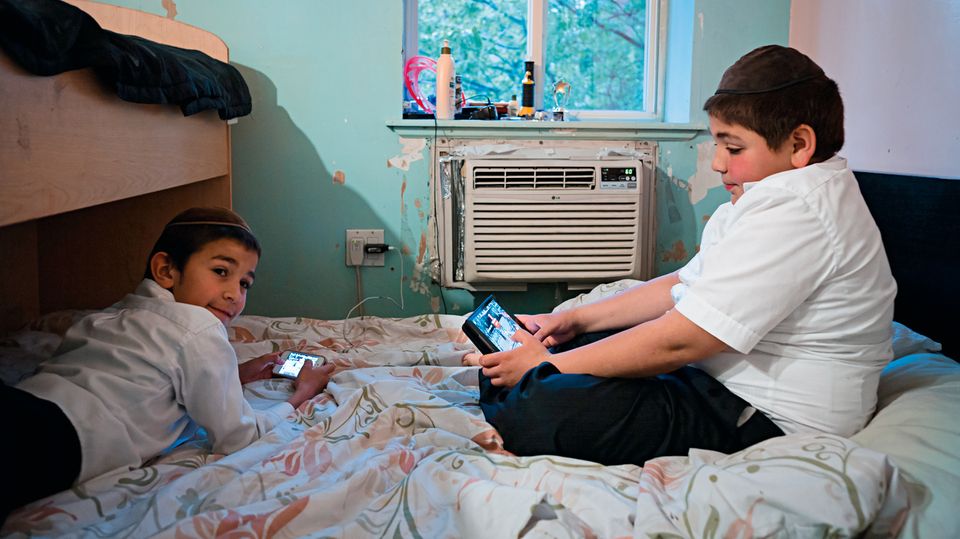 Orthodoxe jüdische Glaubensgemeinschaft: Zwei Jungs vertreiben sich während der Hochzeitsfeier von Bassy Schmukler und Chaim Landa die Zeit mit elektronischen Geräten. Bei Chabad sind sie erlaubt, in der Glaubensgemeinschaft Satmar dagegen verpönt Zwei Jungs vertreiben sich während der Hochzeitsfeier von Bassy Schmukler und Chaim Landa die Zeit mit elektronischen Geräten. Bei Chabad sind sie erlaubt, in der Glaubensgemeinschaft Satmar dagegen verpönt