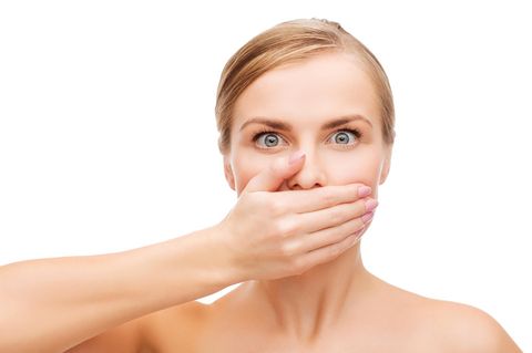 Eine junge Frau hält sich die Hand vor den Mund