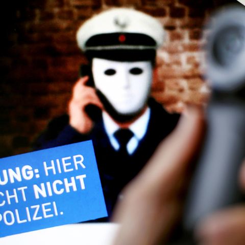 Ein Telefonhörer vor einem Plakat der Polizei NRW mit der Aufschrift "Achtung: Hier spricht nicht die Polizei"