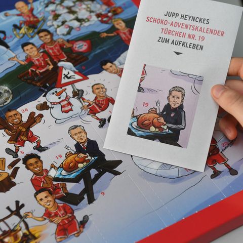Eine Hand hält einen Aufkleber mit Jupp Heynckes vor einen Adventskalender von FC Bayern München