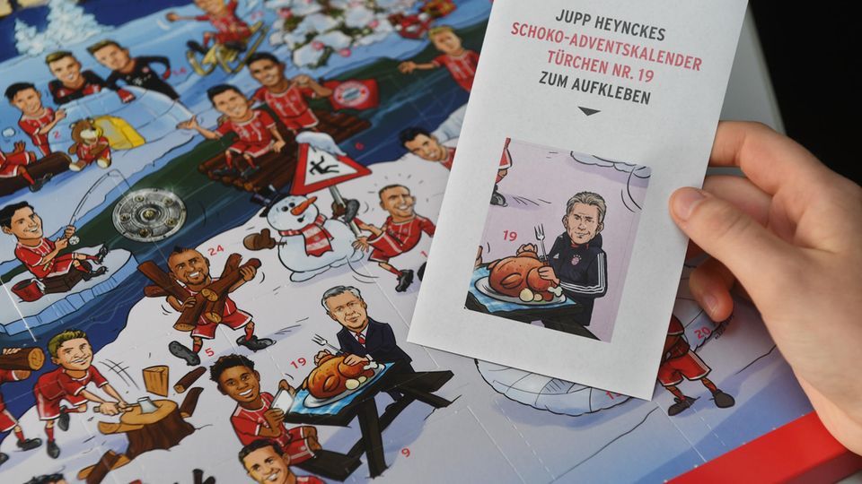 Eine Hand hält einen Aufkleber mit Jupp Heynckes vor einen Adventskalender von FC Bayern München
