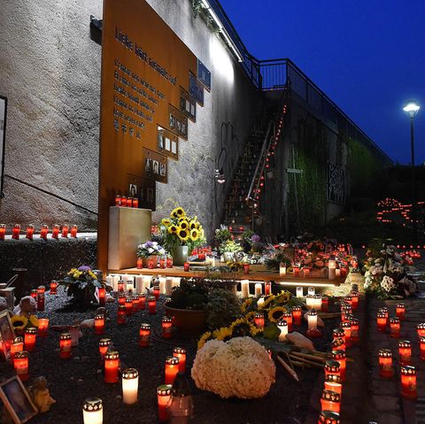 Menschen legen Blumen und Kerzen nieder an der Gedenkstätte zur Loveparade 2010 in Duisburg