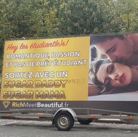 Ein Anhänger mit einem Werbeplakat für ein Sugardaddy-Datingportal steht in Paris am Straßenrand