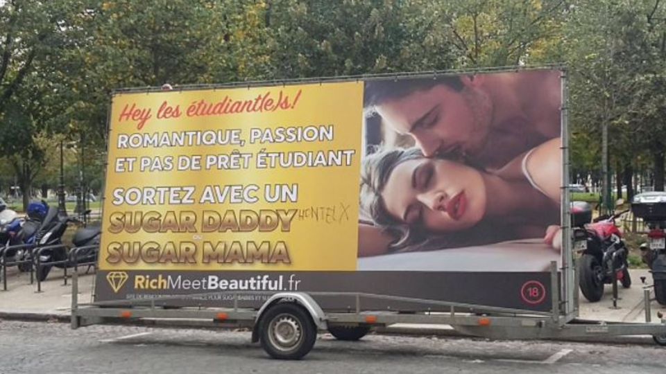 Ein Anhänger mit einem Werbeplakat für ein Sugardaddy-Datingportal steht in Paris am Straßenrand