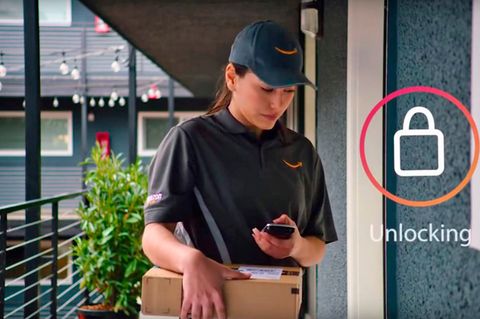 Eine Amazon-Mitarbeiterin öffnet mit ihrem Smartphone die Tür eines Kunden