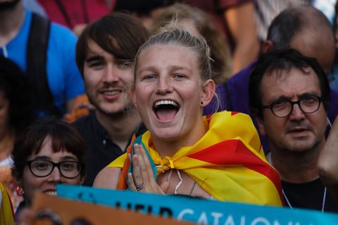 Eine blonde junge Demonstrantin mit katalanischer Flagge um die Schultern freut sich sichtlich über die Unabhängigkeit