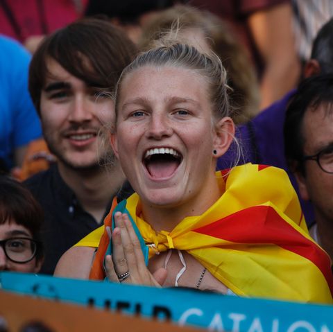 Eine blonde junge Demonstrantin mit katalanischer Flagge um die Schultern freut sich sichtlich über die Unabhängigkeit