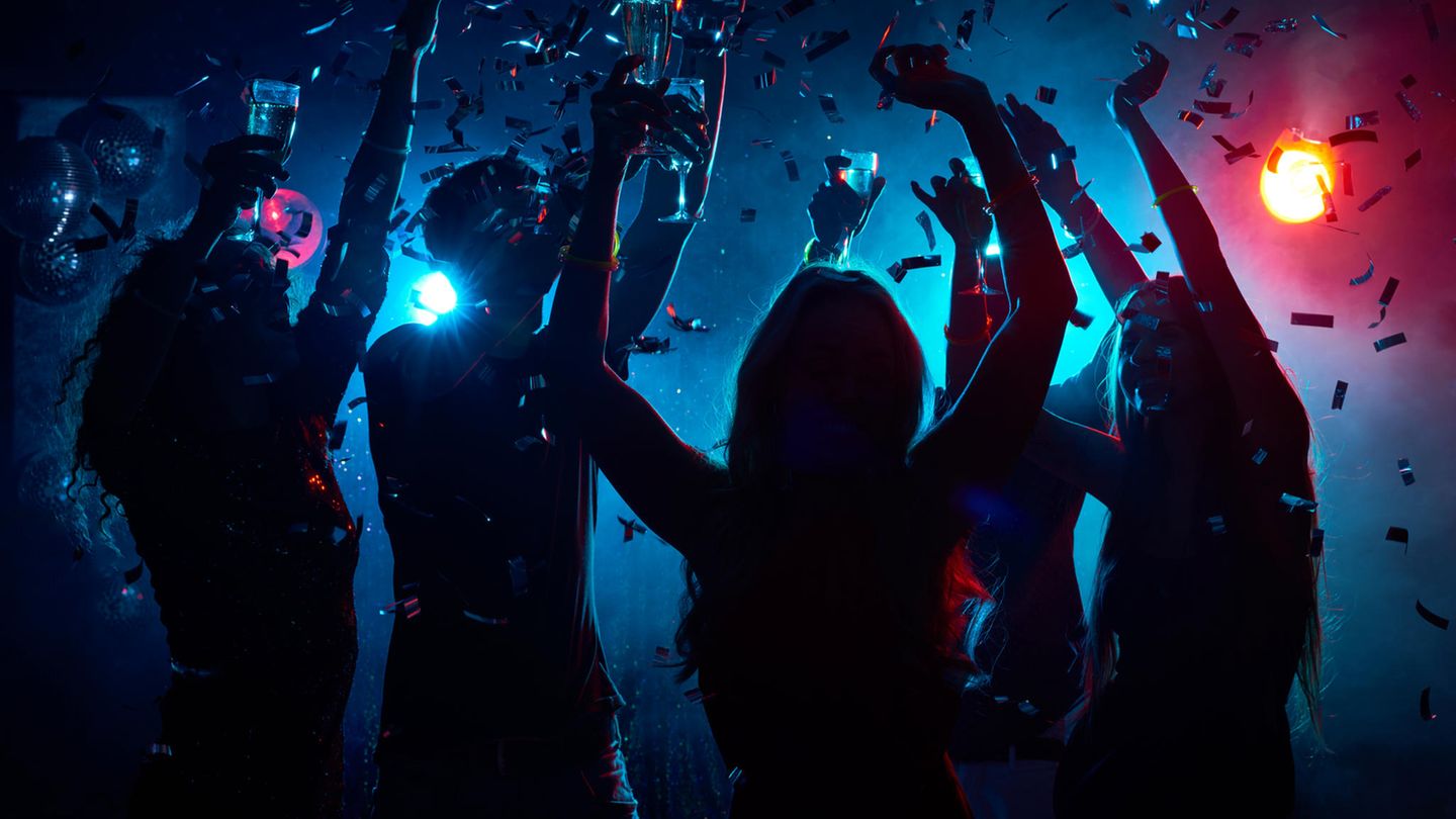 Die Silhouetten tanzender Frauen setzen sich im Gegenlicht eines Nachtclubs ab