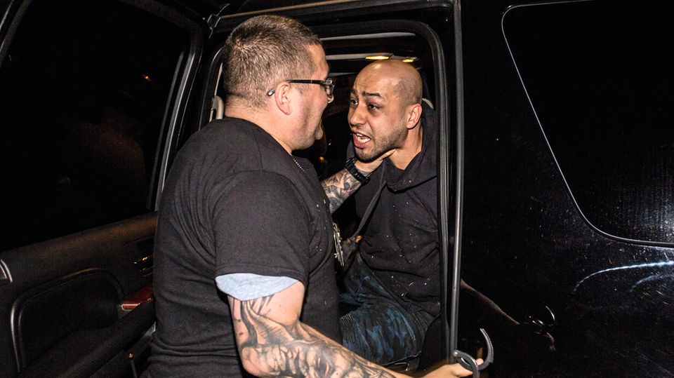 McCall bugsiert Omar El Dilemi, den Mann, den er gerade mit Pfefferpistole im Anschlag niederdrückte, in sein Auto