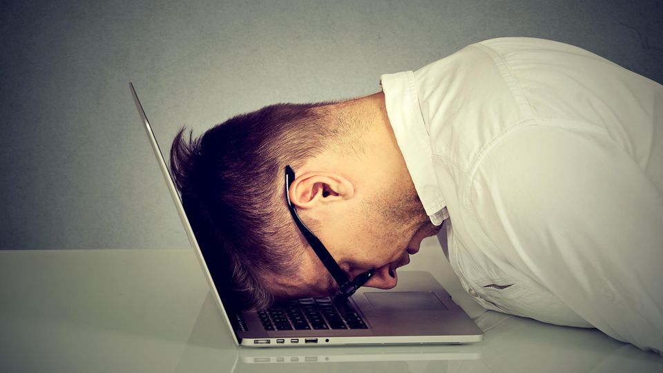 Ein Mann legt verzweifelt seinen Kopf auf den Laptop