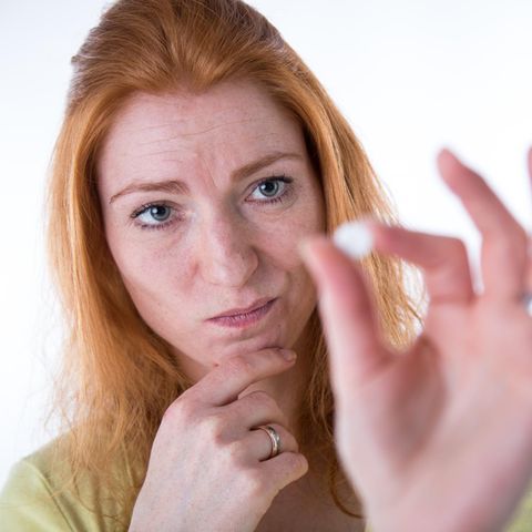 Eine Frau betrachtet skeptisch die Pille