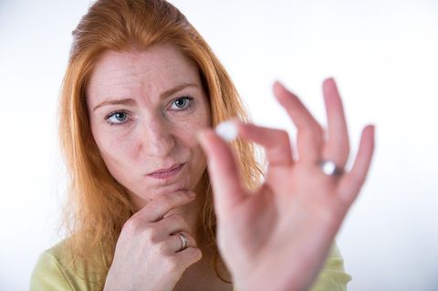Eine Frau betrachtet skeptisch die Pille