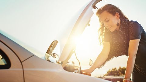 Eine Frau steht vor einer geöffneten Motorhaube eines Autos
