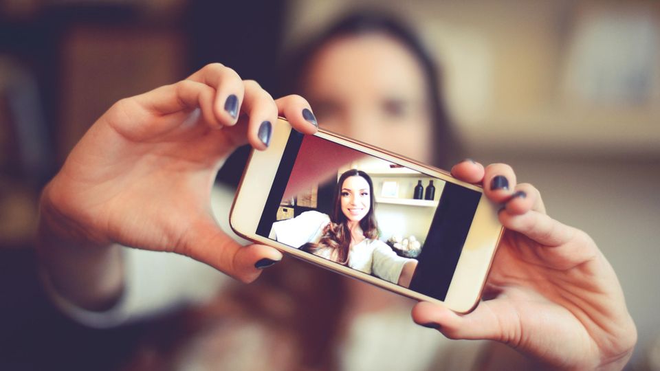 Eine Frau knipst mit der Kamera ihres Smartphones ein Selfie