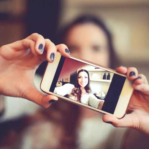 Eine Frau knipst mit der Kamera ihres Smartphones ein Selfie