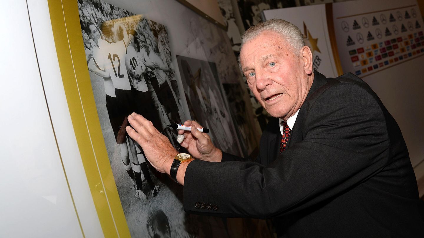 Hans Schäfer setzt sein Autogramm auf einem alten Foto der Fußball-Nationalmannschaft