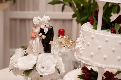Auf einer Hochzeitstorte haben Braut und Bräutigam Sahne im Gesicht