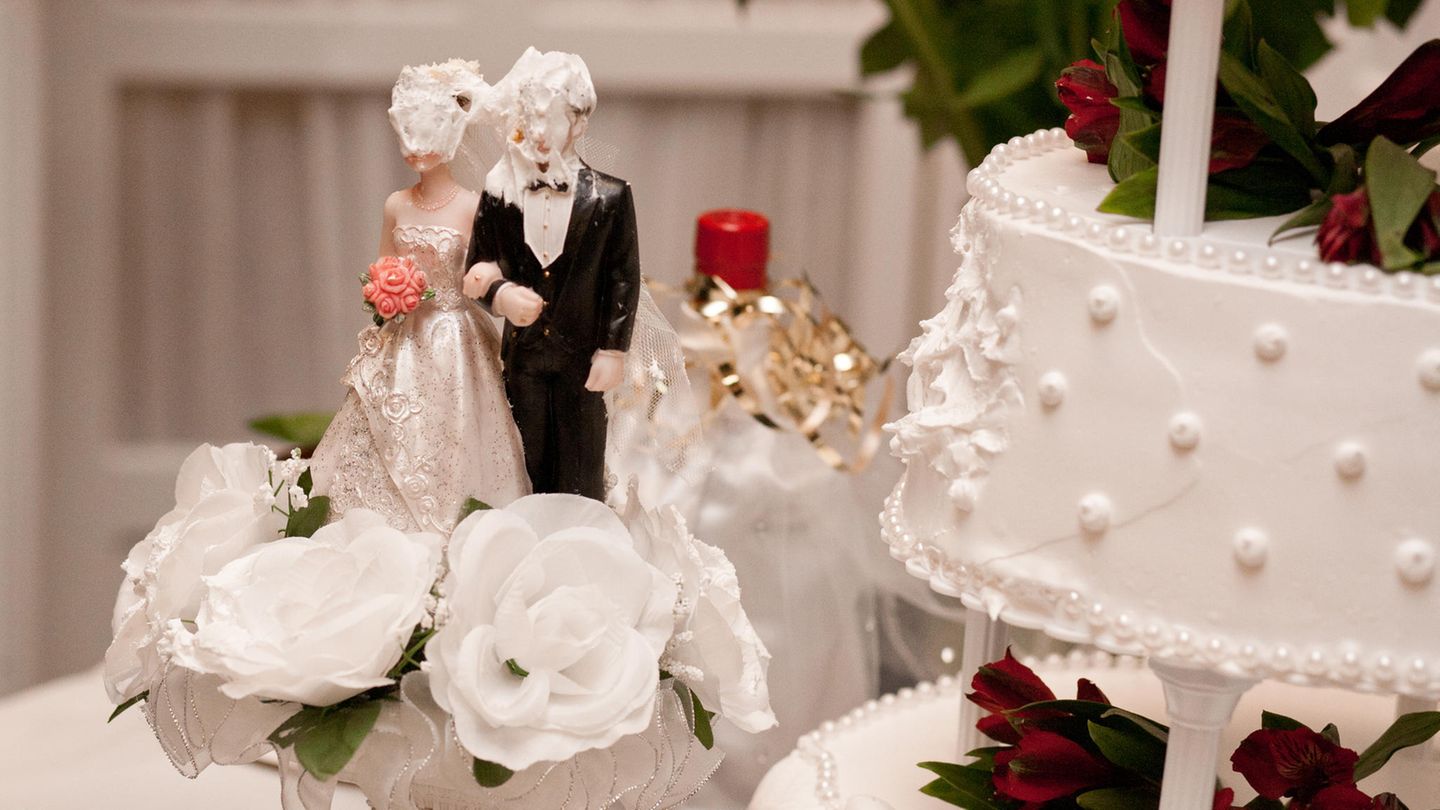 Auf einer Hochzeitstorte haben Braut und Bräutigam Sahne im Gesicht