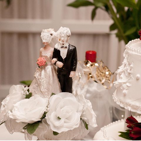 Auf einer Hochzeitstorte haben Braut und Bräutigam Sahne im Gesicht