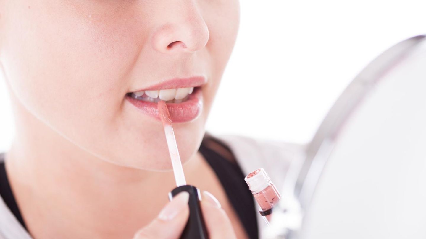 Eine Frau trägt Lipgloss auf ihre Lippen (Symbolbild)