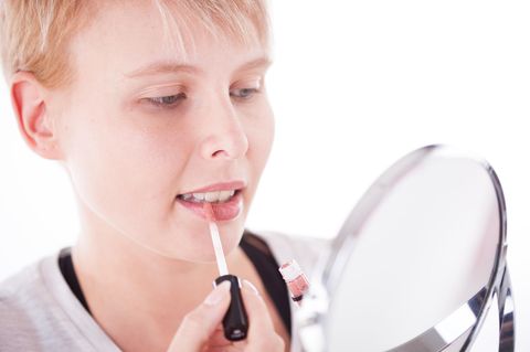 Eine Frau trägt Lipgloss auf ihre Lippen (Symbolbild)