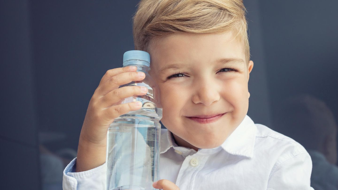 Ein Junge hält seine Trinkflasche und grinst